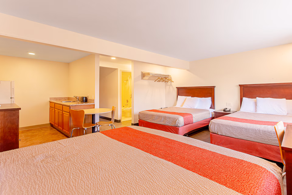 Large guest room with three queen beds and a kitchenette